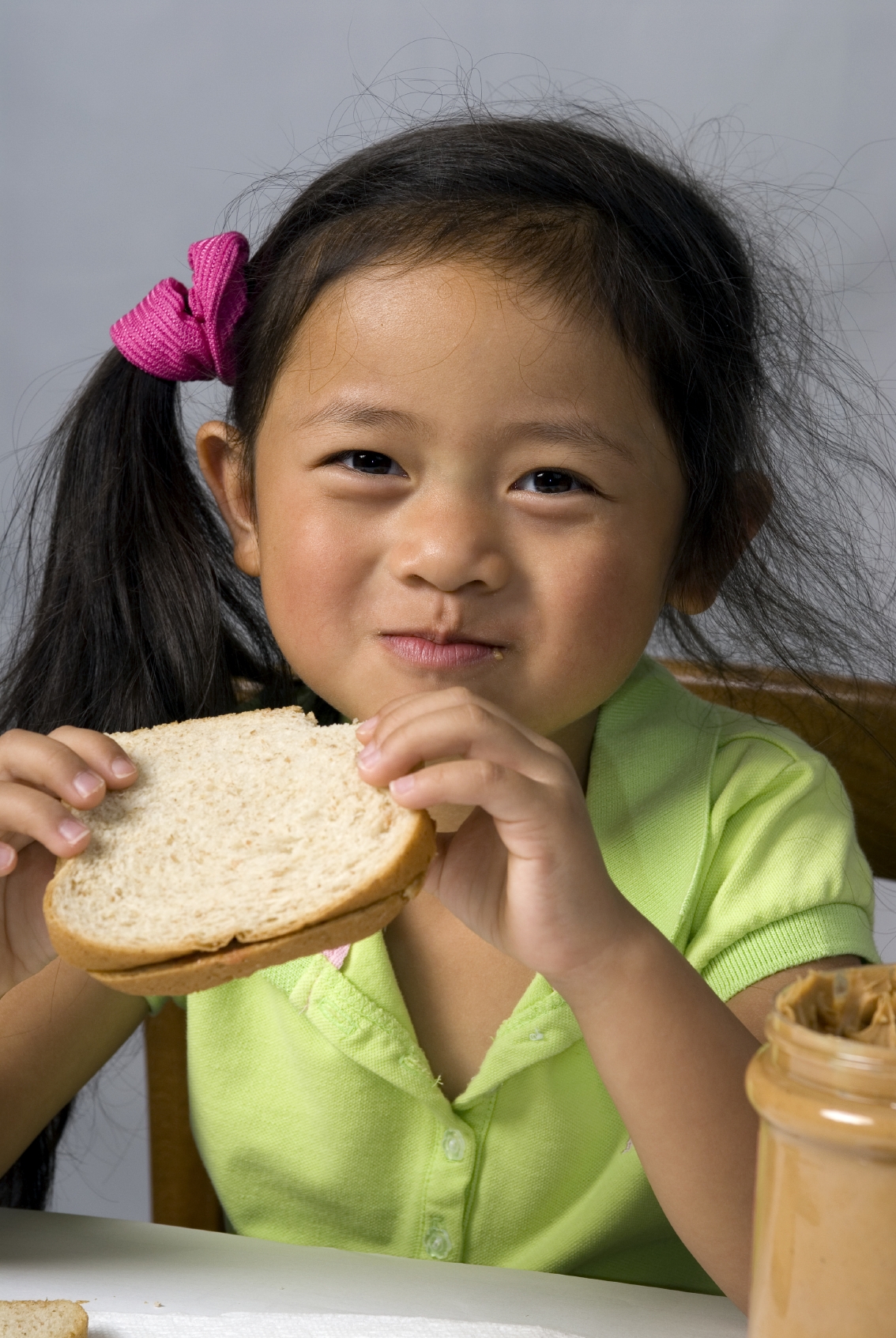 A young child makes a peanut butter and Jelly sandwich