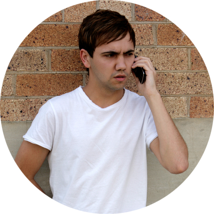 Guy on Cellphone by Brick Wall