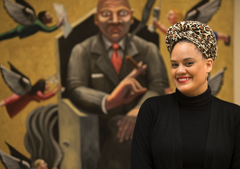 Lhorna Murray – artist, activist, community organizer & Sand Point Housing resident – poses in front of ‘Office Deity’ by Pacific NW artist John Feodorov (photo by Chris Villiers | Writing, Photography & Strategic Communications).