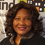 Headshot of a Black woman in a black shirt in front of a Solid Ground banner