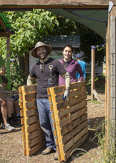 Two Google employees haul pallets at a Giving Garden at Marra Farm work party, summer 2018