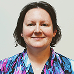 Smiling headshot of a woman with short brown hair, wearing a teal and purple print shirt