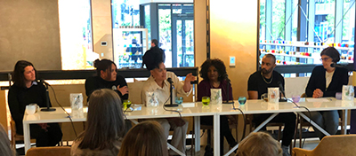 Six people sit behind microphones at a long table.