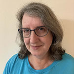 Headshot of a greying woman wearing glasses and an aqua shirt.