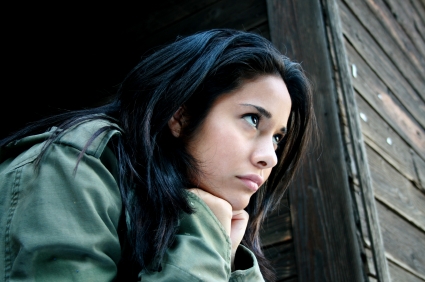 Latinx teen looks sadly with her chin resting on her hands