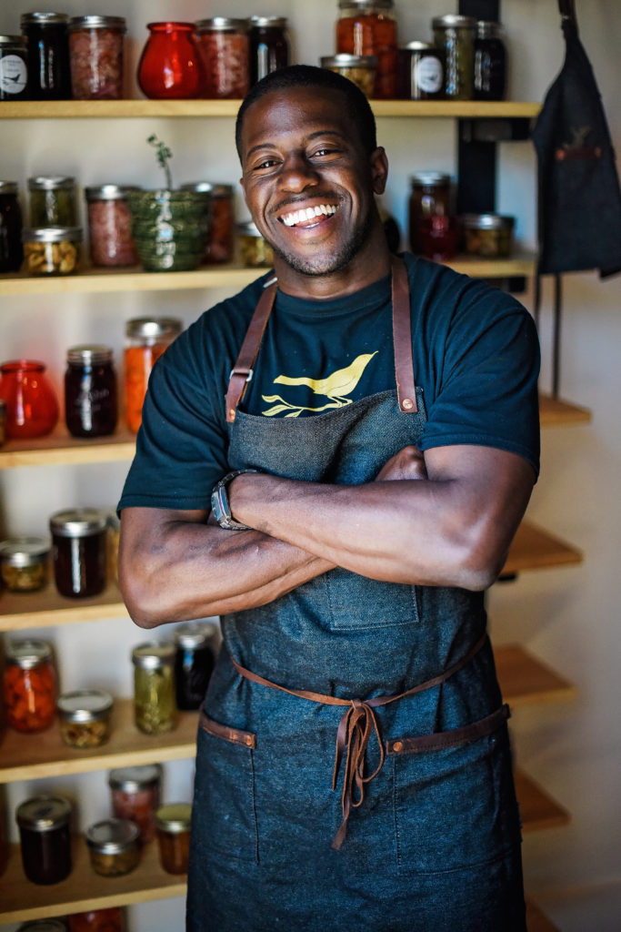 Acclaimed Seattle Chef Edouardo Jordan surrounded by jars of pickled foods