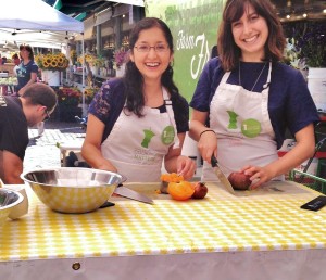 Sandra & Addie prepare food in the sun at a cooking demo at Pike Place Market.