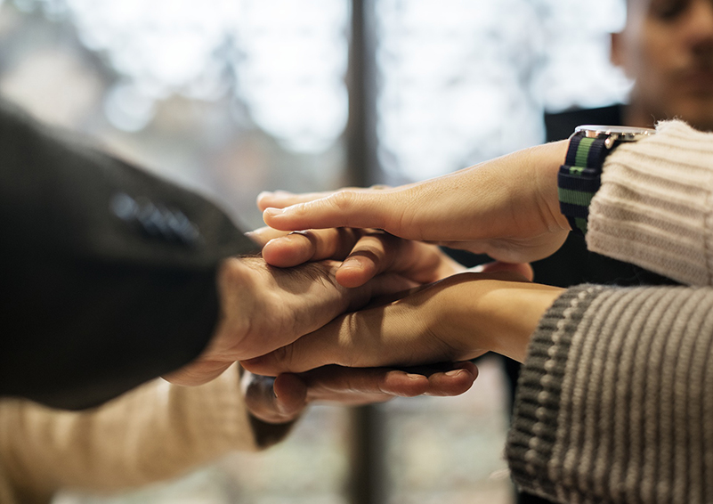 Hands stacked in a "go team" collaboration stance