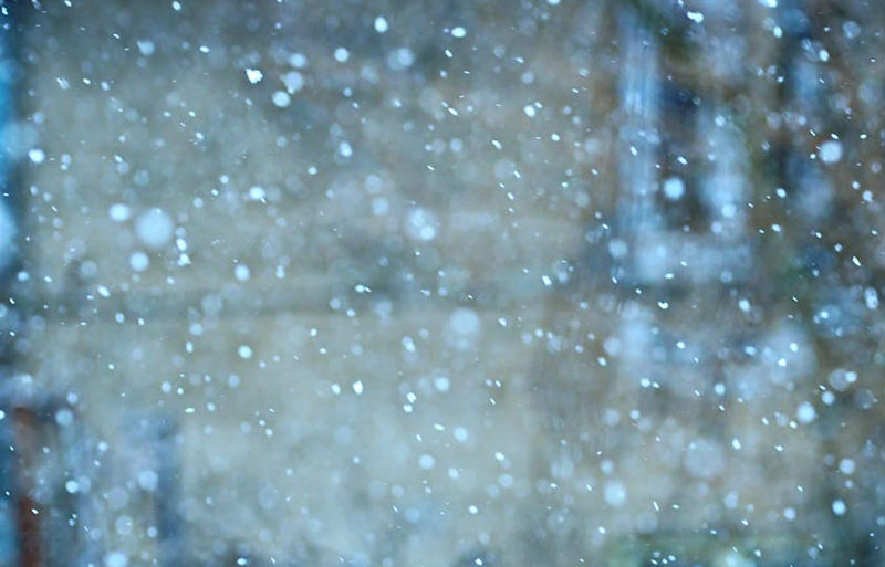 Snow falling in front of brick building
