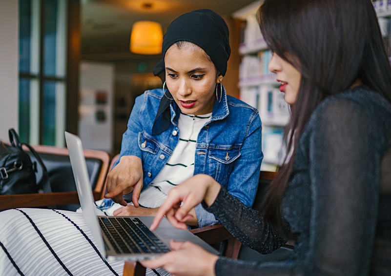 Two women looking and pointing at a shared laptop