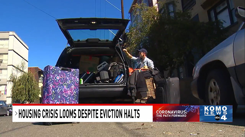 Screenshot from KOMO News story of a man in a cap and sunglasses loading belongings into the back of a station wagon; caption reads, HOUSING CRISIS LOOMS DESPITE EVICTION HALTS