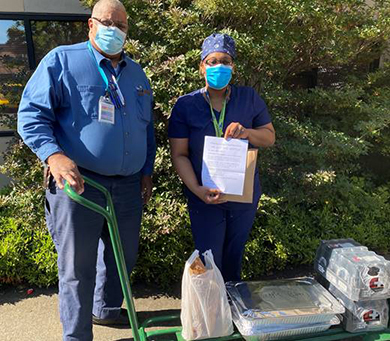 Two people holding a cart of donated food