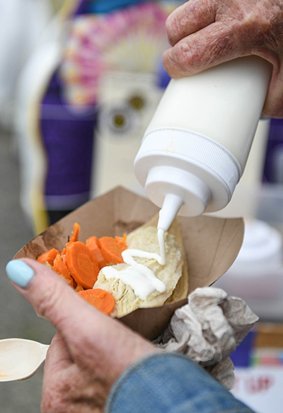 A hand holding a to-go serving of tamales