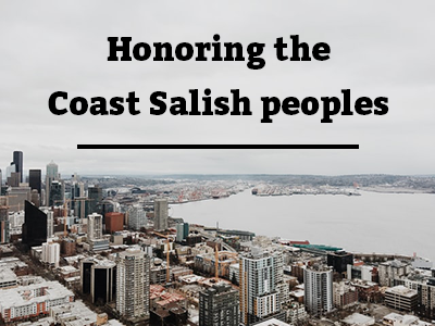 Photo of the downtown Seattle waterfront with a grey sky and black text reading Honoring the Coast Salish People