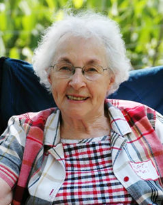 Photo of an elderly white woman with white hair and glasses, smiling