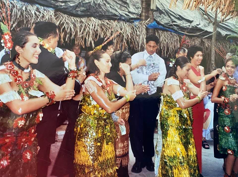 Group of Tongan women in colorful dresses dancing at a wedding