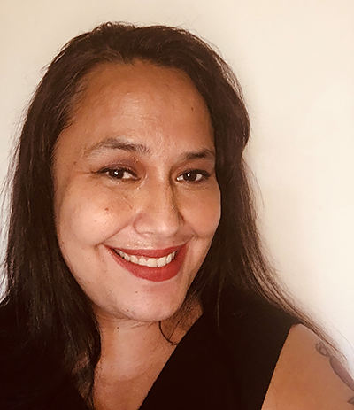 Headshot of a Tongan American woman smiling with dark brown hair, wearing a black tank top