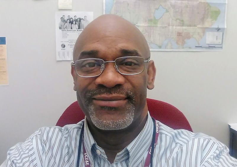 A picture of Kirk McClain wearing glasses and sitting in a desk chair