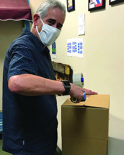Senior male volunteer boxes food in a food pantry