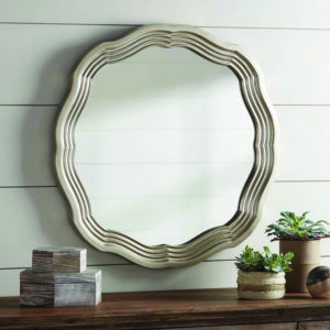 a large silver scallop-shaped mirror above a wooden table