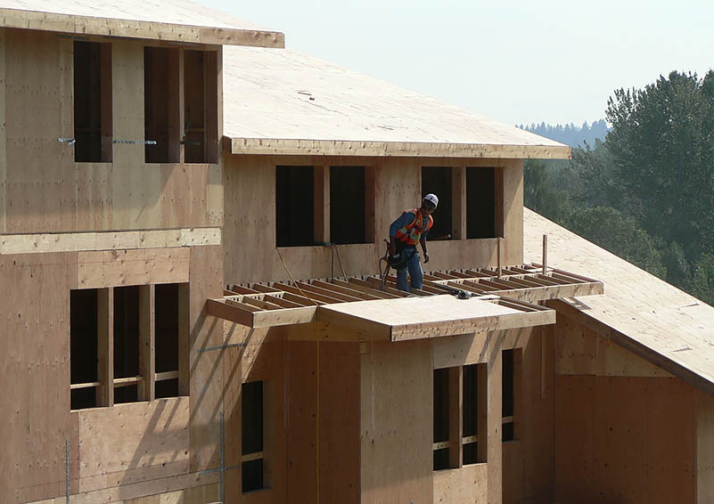 A construction worker stands on the roof of a building under construction