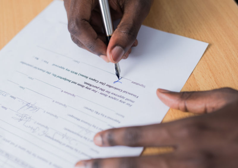 Close up of someone signing their name on a piece of paper