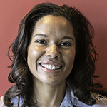 Headshot of a Black woman in a white button-down shirt with blue background.