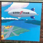 A painting of a Good Year blimp gliding over the Sand Point penninsula.