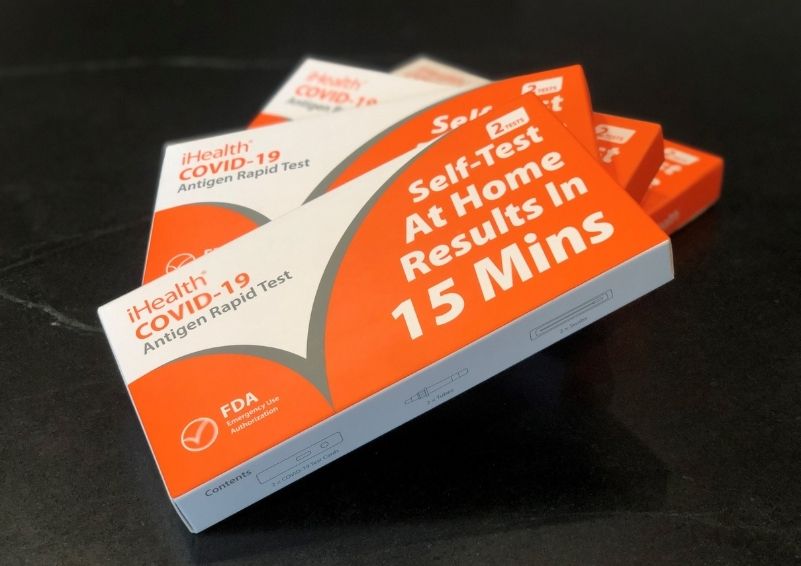 Several orange and white boxes of at-home COVID-19 tests splayed out on a table
