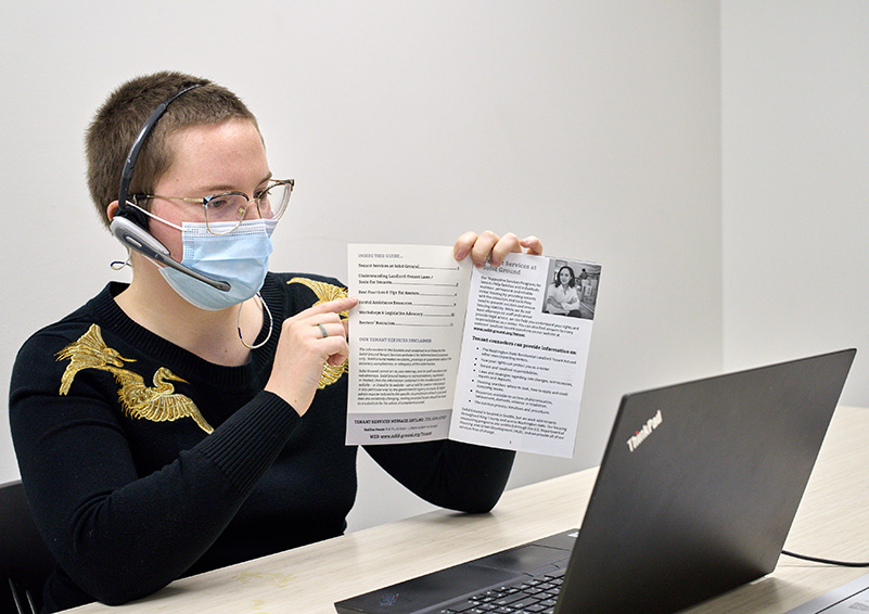 A person in a headset points at a handout while facing a laptop. She's leading a webinar on tenant rights.