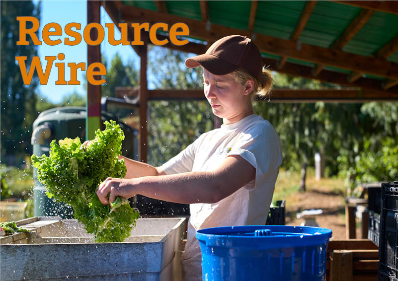 A young woman in a t-shirt and brown baseball hat shakes water from a head of lettuce over an outdoor sink. The words Resource Wire appear above her.