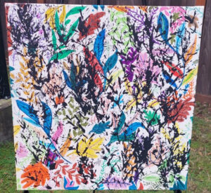 A painting of many colors across a white canvas, many of them taking the shape of leaves.