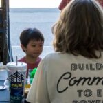 A young boy talks to a woman wearing a Solid Ground tshirt.