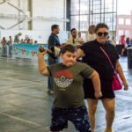 A young boy winds up to throw an inflatable axe-shaped toy while a woman looks on.