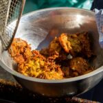 Food fresh from the fryer is dumped into a metal bowl.