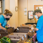 Solid Ground staff restock the table of vegetables at FARMacia.