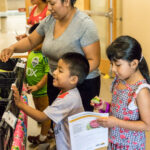 A mom and two children look through vegetables available at FARMacia.