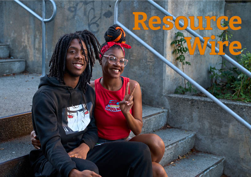 A young couple smiles as they sit together on a concrete staircase outdoors. One of them, a young women in a red Spiderman tank top and her braids tied up in a top knot, flashes the peace sign with one hand. The words "Resource Wire" appears above them.